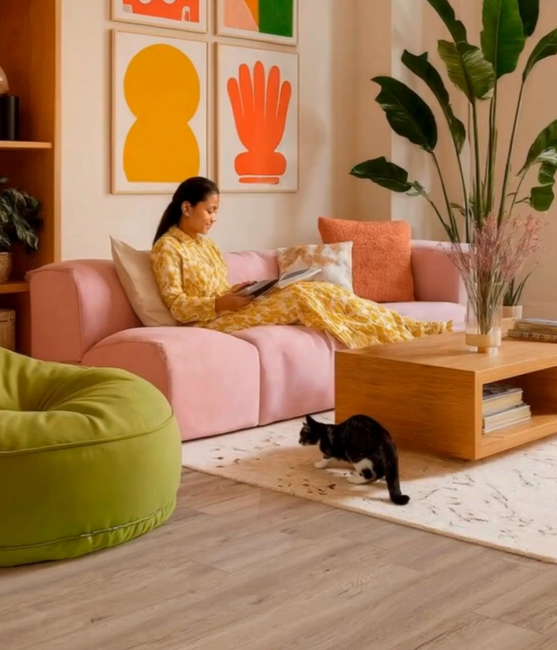 A woman reading in a room with a cat sitting on the kiwi now floor